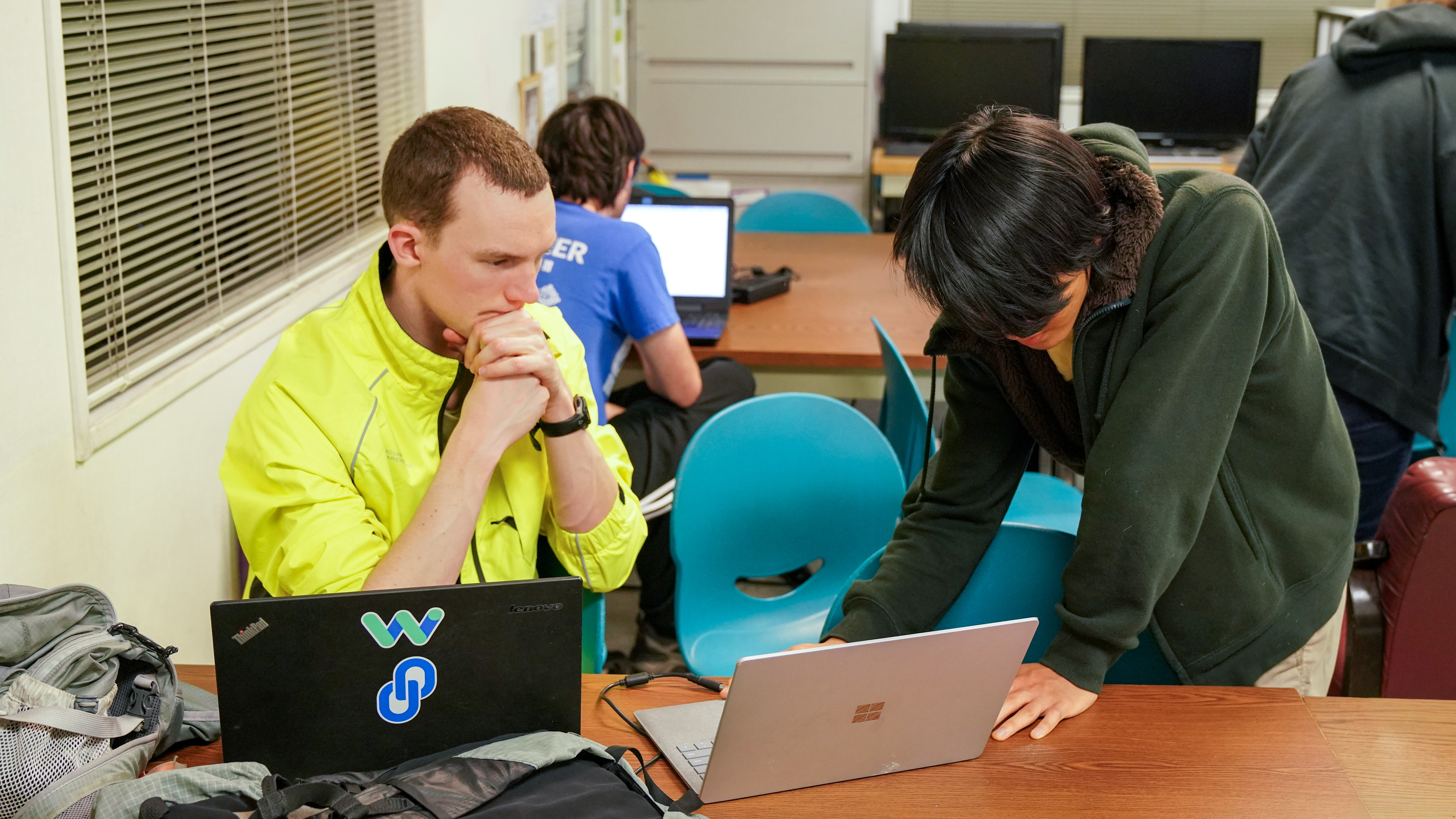James helping a high school student debug code on a laptop at a FIRST Robotics event